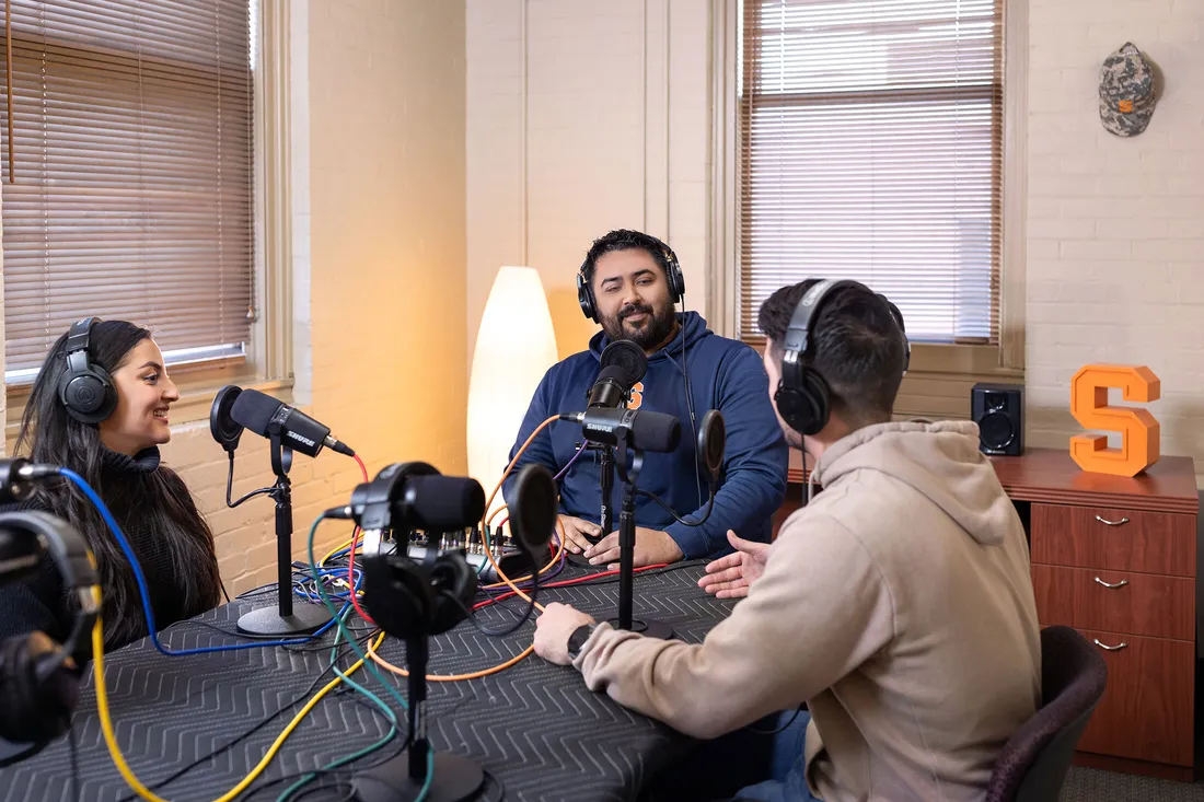 Three people together in a podcast studio.