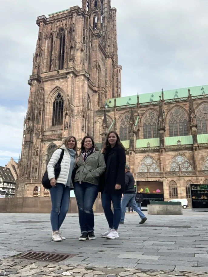Julia Yahres standing with her mom and aunt in front of Strasbourg Cathedral.